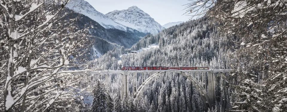 Eisenbahn fährt im Winterwunderland über eine Brücke
