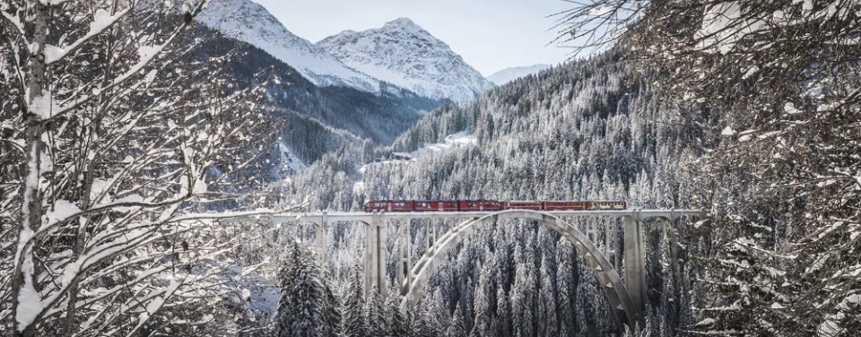 Eisenbahn fährt im Winterwunderland über eine Brücke