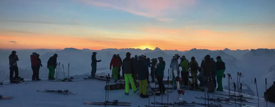 Viele Skifahrer bei Sonnenuntergang auf dem Berg