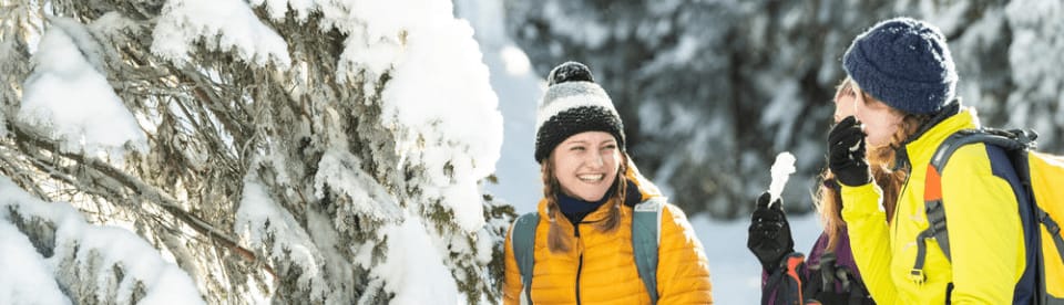 Zwei Frauen lachen sich im Schnee an