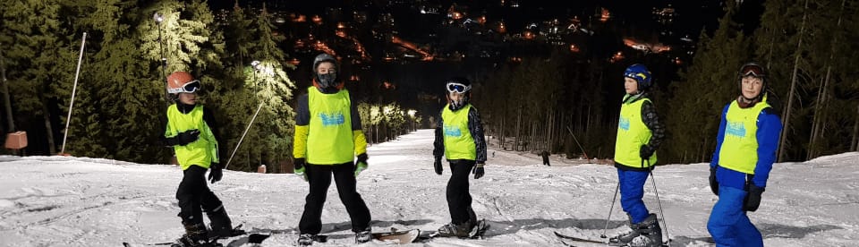 Kindergruppe auf Piste beim Nachtskifahren