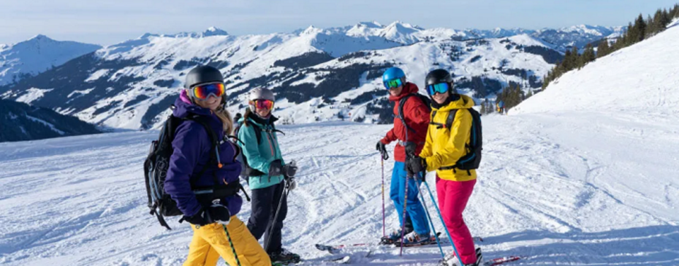 Vier Skifahrer warten lachend auf der Piste