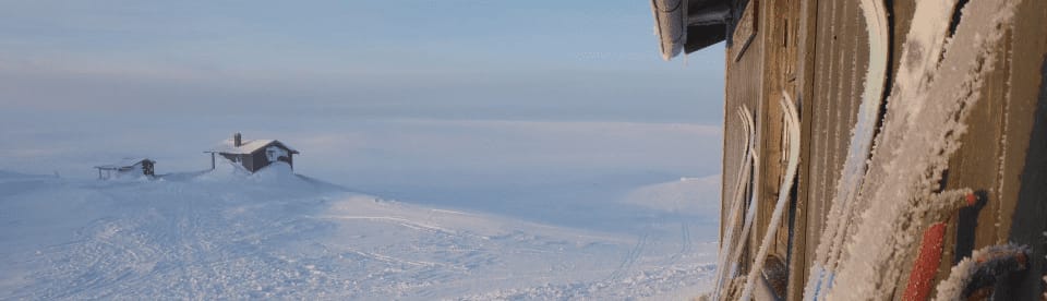 Ski vor Hütte und weißer Landschaft