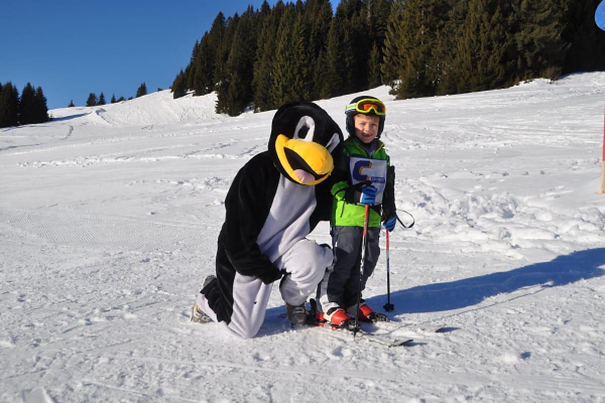 Kind mit Skiern und Pinguin auf der Familienfreizeit Saalbach