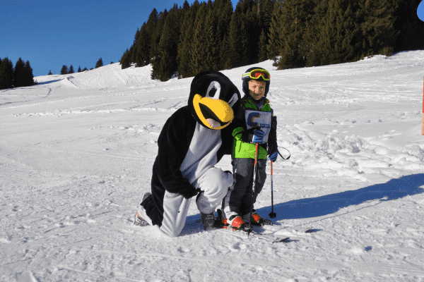 Kind mit Skiern und Pinguin auf der Familienfreizeit Saalbach