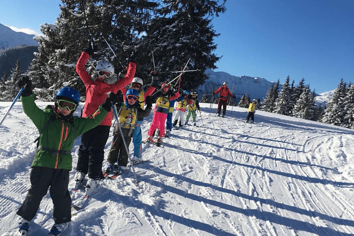 Skikurs hebt die Arme in die Luft