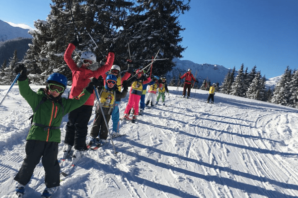 Skikurs hebt die Arme in die Luft